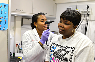 An RBHS medical student inspects a patient's ear